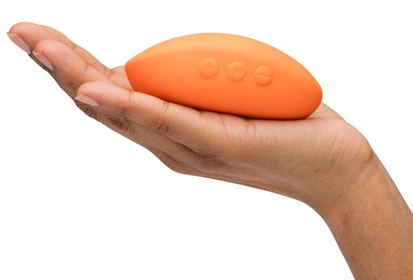 Orange We-Vibe Temp personal massager in a hand on a white background