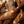 Person using an orange handheld device on another person's leg in a home setting.