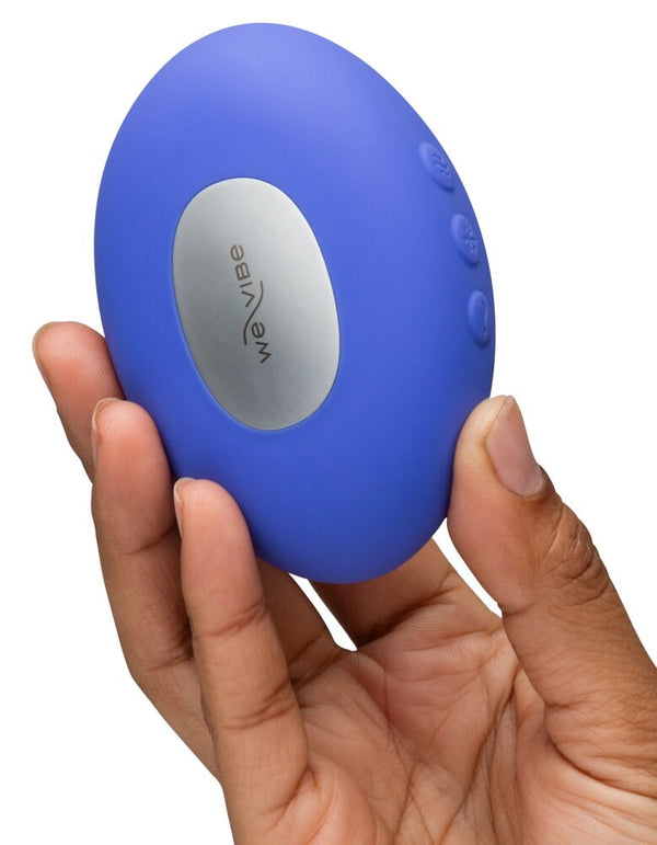 Handheld personal massager with the branding for We-Vibe on a silver panel on the front being held in front of a white background.