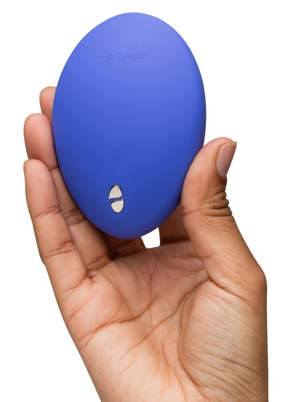A hand holding a small, oval-shaped blue personal massager against a plain white background.