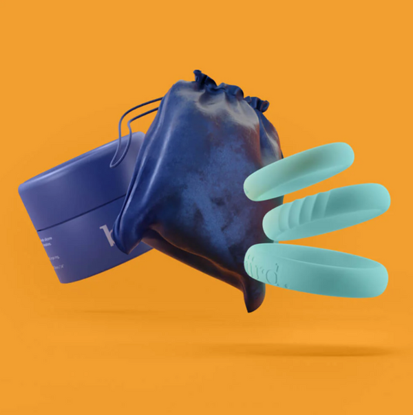 Biird Riin Silicone Cock Ring Set in light blue. Shown on an orange background alongside a navy blue bag and container 