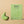 Kiwi therapeutic pelvic health vibrator next to its green box in front of a peach coloured background
