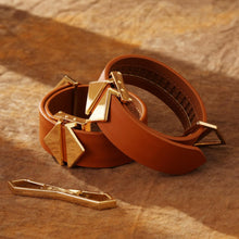 Load image into Gallery viewer, Side view of LOCKINK Leather Cuffs laid on top of one another with a rustic straw coloured background. Alongside a LOCKINK buckle.