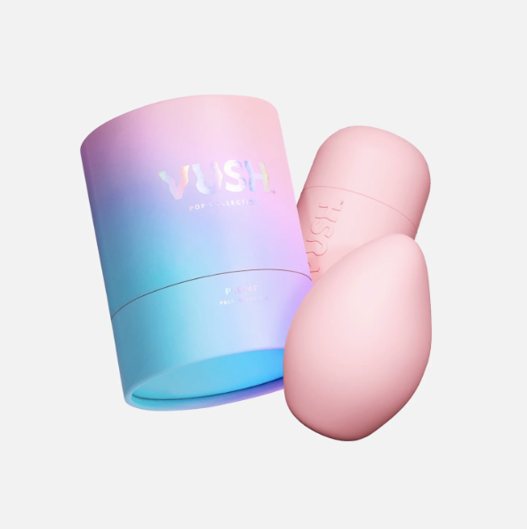 VUSH Plump Rechargeable Palm Vibrator in light pink alongside its cap and case.