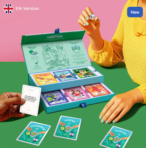 Open box of Together Intimacy Card Game by Biird next to a person wearing a yellow top, and another hand holding a card.