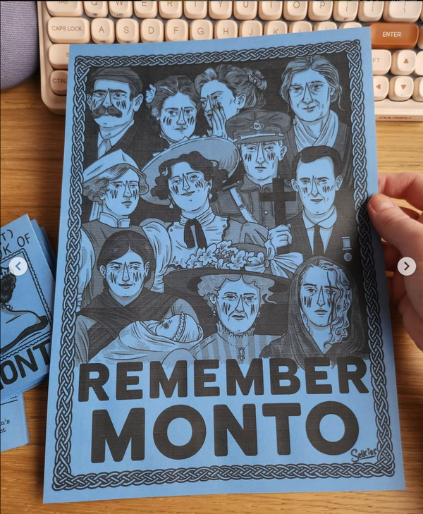 Hand holding the fold out poster made from the blue education zine about Monto, by the artist Selkies. Over a brown table background and other zines.