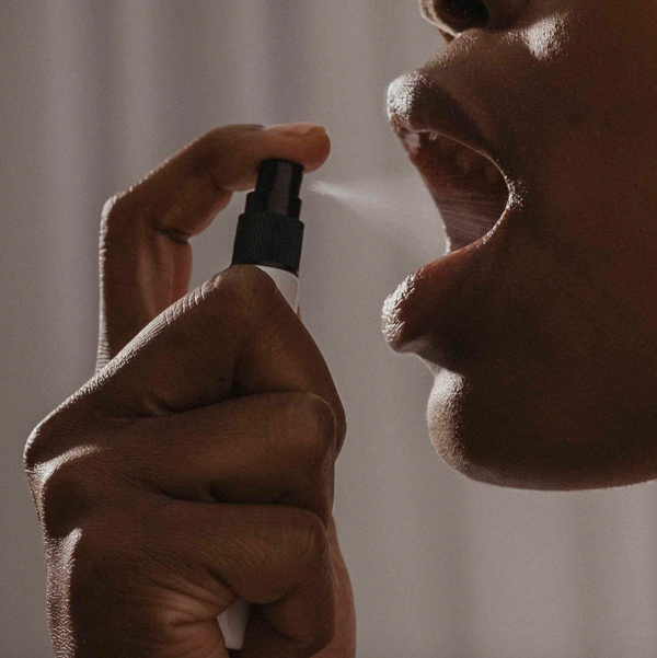 Hand spraying Slow Sex Mouthwatering Spray into open mouth