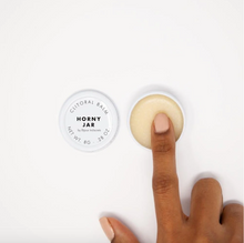 Load image into Gallery viewer, Open jar of Bijou Indiscreets Horny Jar Clitoral Balm alongside the lid, with finger swiping some of the contents