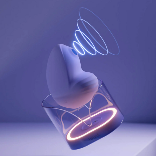 Biird Namii Rechargeable Dual "Sucker" & Vibrator in lilac. Shown in its lilac hued holder with haloes of light emanating from the sucker. Presented on a lilac/purple background.
