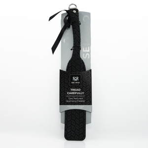 Tyre Tread Spanking Paddle in packaging with ribbon tied to hanger and clear flexible tyre marked paddle - Sex Siopa stocks Ireland's best sex toys, lubricants and accessories. 