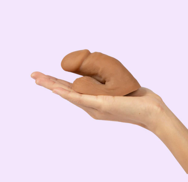 hand holiding the Wet For Her Quinn packer in front of a lavender background