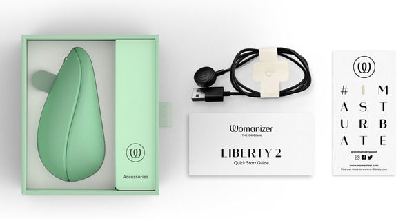 Full packaging of the Womanizer Liberty 2 Rechargeable "Sucking" Vibrator in shades of green and white. Alongside the user guides and charger cables.