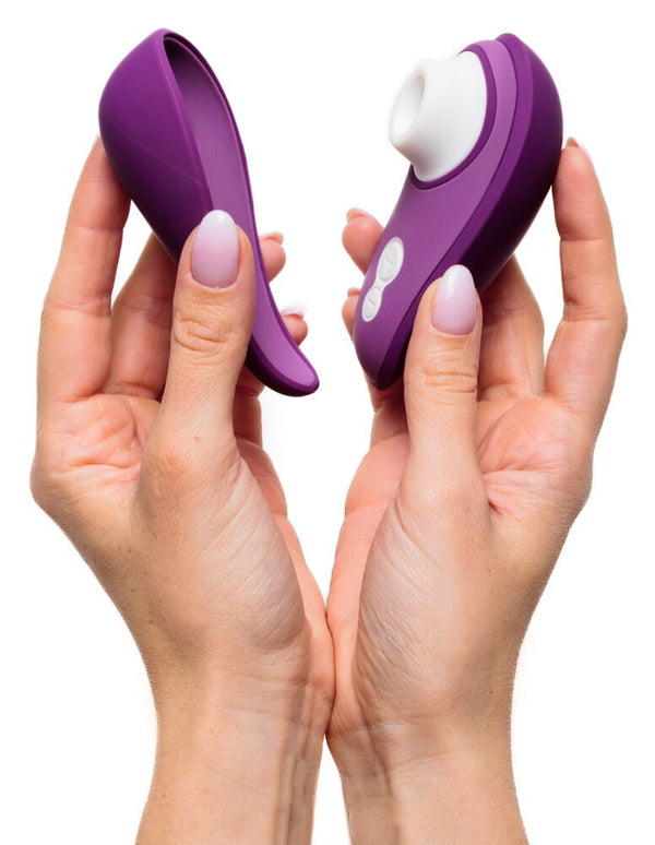 Hands holding a Womanizer Liberty 2 Rechargeable "Sucking" Vibrator in purple and white, along with its cover.