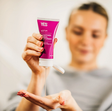 Load image into Gallery viewer, A menopausal woman squeezes a bottle of Yes VM vaginal moisturizer into her hand.