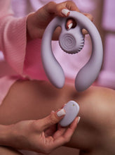 Load image into Gallery viewer, A woman in a pink nightgown holds the SVibe Snail Gizi duo couples' vibrator in one hand and the rechargeable remote control in the other.