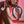 A woman with a french manicure is sitting on the floor in pink pajamas holding the Snail Gizi Duo couples vibrator in one hand over her knee and the remote control in her other hand. 