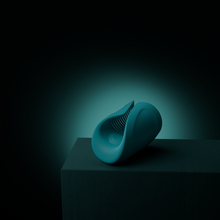 Load image into Gallery viewer, Horizontal Turquoise coloured Gush penis massager by Lovense, laid on a stand with a turquoise shadowy background.