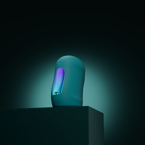 Vertical Turquoise coloured Gush penis massager by Lovense, stood on a stand with a turquoise shadowy background.