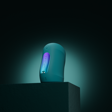 Load image into Gallery viewer, Vertical Turquoise coloured Gush penis massager by Lovense, stood on a stand with a turquoise shadowy background.