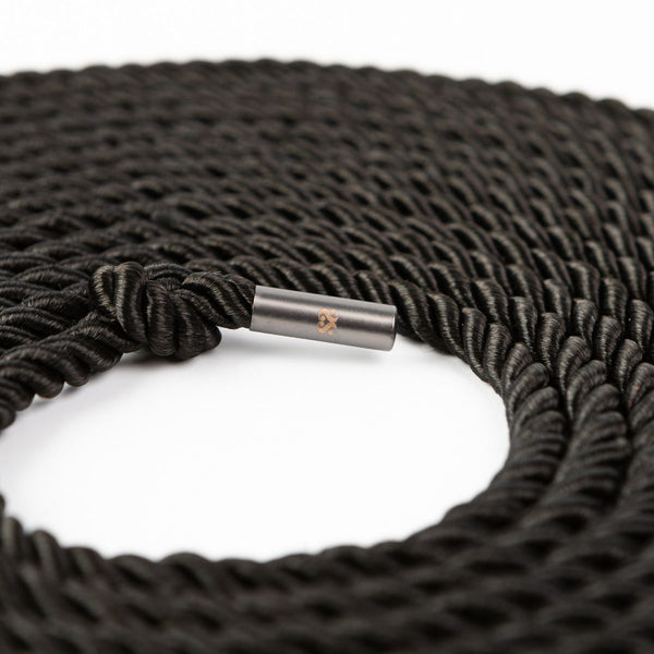 Close up of the wrapped up SEI MIO - Knot in Control - 10m Silky Bondage Rope in black on a white background.