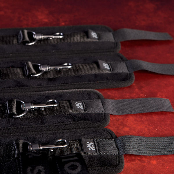 Clip components of the Sei Mio Bed-Spreader Under Bed Restraint System in black, laid out on a red background