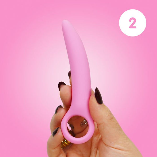 Woman's hand holding size 2 of the Skins Care silicone dilator set against a pink background.