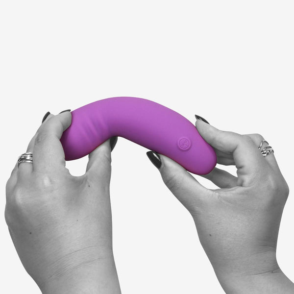 The Skins glee spot rechargeable vibrator being bent in the middle by a woman's hands to show off its flexibility.