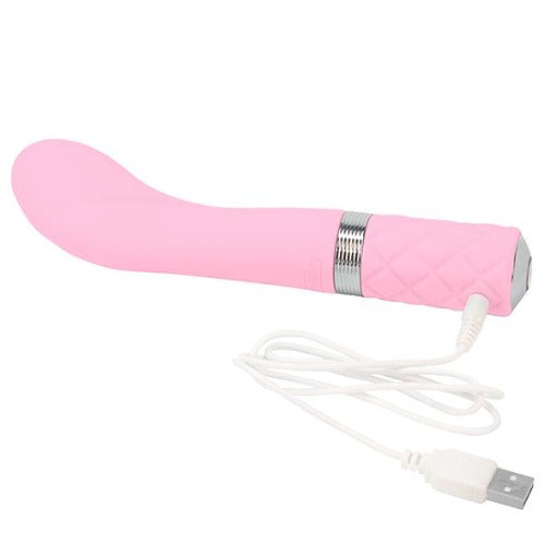 A white cabled charger in place on the Sassy rechargeable G-spot vibrator by Pillow Talk in pink. Laid on a white background