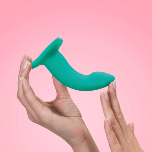 Picture of female hands holding the Fun Factory Limba Flex small, a bendable flexible silicone dildo that's perfect for using with a strap-on harness. Coloured in dark green this is set on a light pink background. The Limba Flex comes in a small and medium size. Available at SexSiopa.ie, Ireland's favourite sex toy retailer.