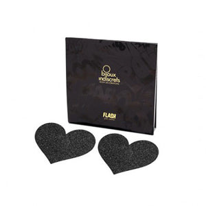 Two black heart shaped glitter nipple stickers alongside their packaging. Set on a white background.