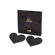 Two black heart shaped glitter nipple stickers alongside their packaging. Set on a white background.