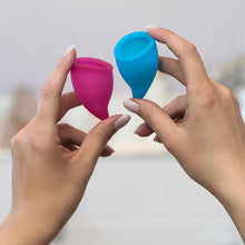 Load image into Gallery viewer, Hands holding the Fun Factory silicone reusable menstrual cups - Sex Siopa, Ireland&#39;s best online sex toy shop